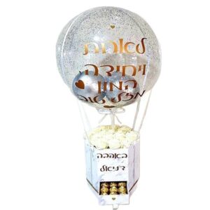 בלון שקוף גדול עם כיתוב אהבה מעל מארז לבן ובו סידור בהיר ומתוקים